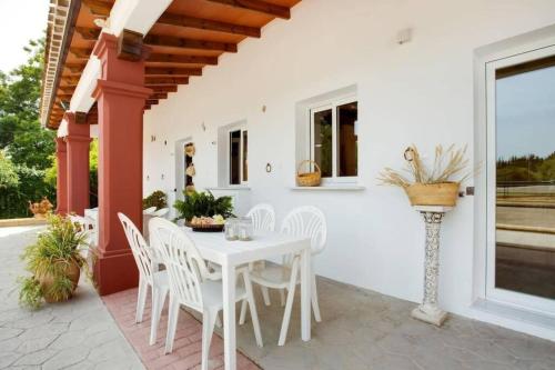 - une table et des chaises blanches sur la terrasse dans l'établissement Finca El Altabacar - Casa Rural - Playa, à Mijas