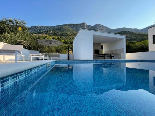 uma villa com uma piscina com montanhas ao fundo em Tole Villa Podaca 2 with heated Pool em Podaca