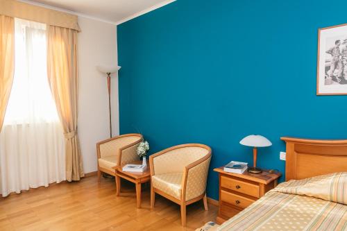 a bedroom with two chairs and a blue wall at Hotel Spongiola in Krapanj