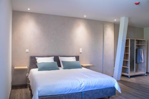a bedroom with a large white bed with blue pillows at B&B elzartwinning in Hasselt