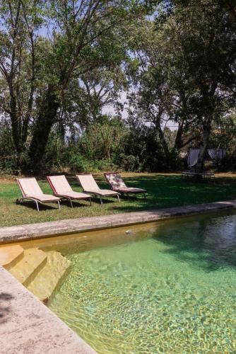 3 chaises longues assises à côté d'une piscine d'eau dans l'établissement Gîte de caractère 72m2, à Rochefort-du-Gard