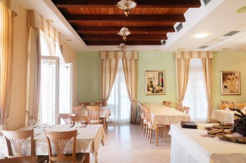 a restaurant with tables and chairs and windows at Hotel Spongiola in Krapanj