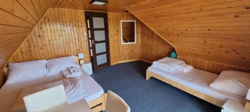 a room with two beds in a wooden cabin at Willa Kotwica - Solina Chrewt in Chrewt