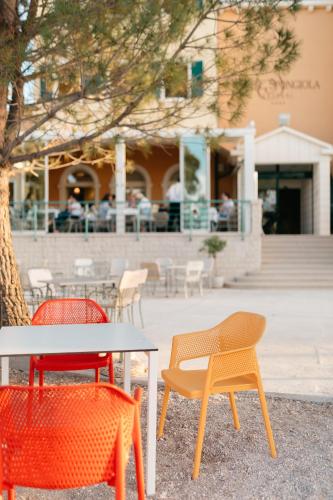 three chairs and a table in front of a building at Hotel Spongiola in Krapanj