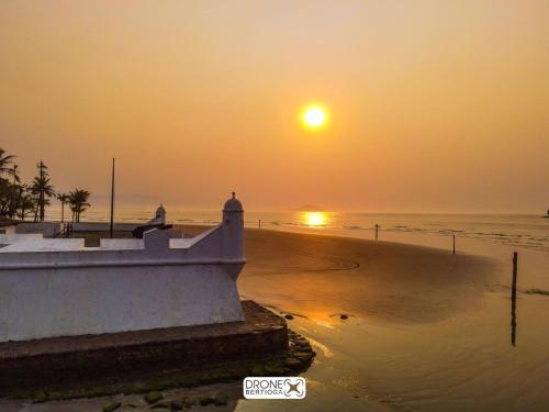 a sunset over a beach with a lighthouse at BERTIOGA suítes na praia centro in Bertioga