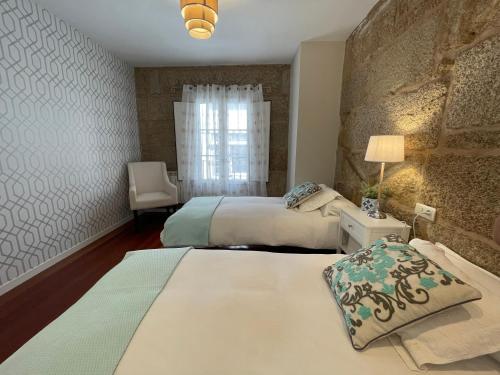 Sweet Home Pontevedra في بونتيفيدرا: غرفة نوم بسريرين وجدار حجري