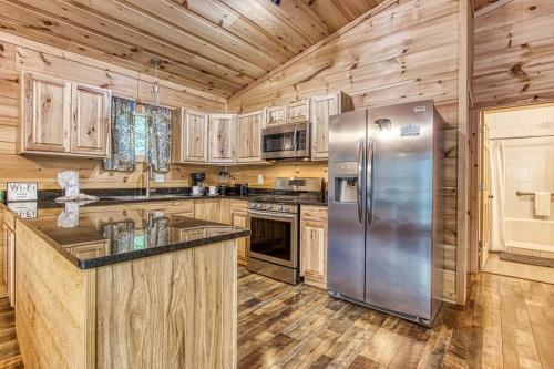 a kitchen with wooden cabinets and a stainless steel refrigerator at Ooglie Bear, Hot Tub, WIFI, Free Attraction Tickets!!! in Gatlinburg