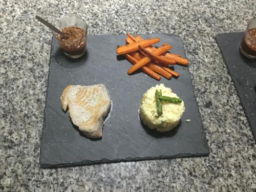 a black cutting board with carrots and mashed potatoes and meat at Villa F&B in Bocas del Toro