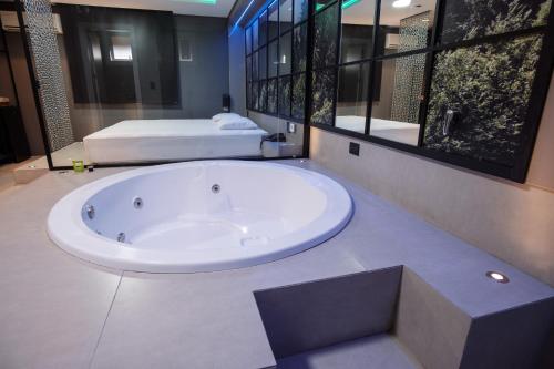 a large bath tub in a bathroom with two beds at Motel Della Montagna (Adult Only) in Bento Gonçalves