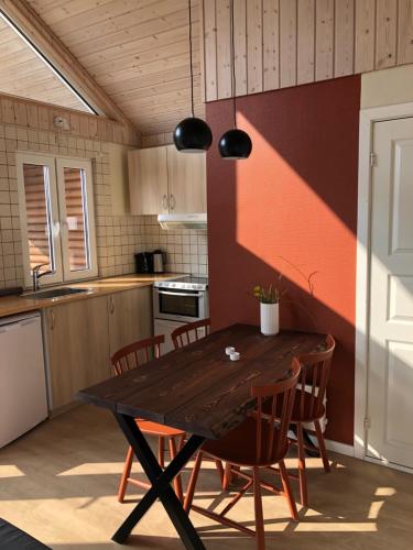 a kitchen with a wooden table and chairs at Emmerbølle Luksushytter med havudsigt in Tranekær