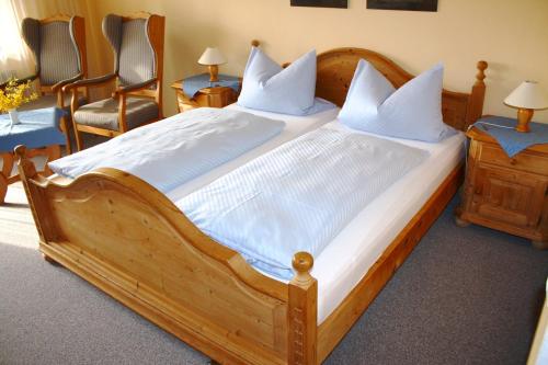 Cama grande de madera con sábanas y almohadas blancas en Appartementhaus Panny, en Bad Füssing