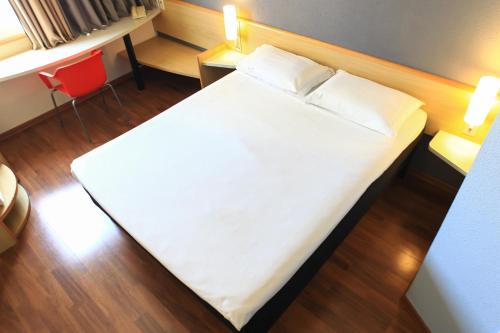 a large white bed in a room with a red chair at ibis Sao Jose dos Campos Colinas in São José dos Campos