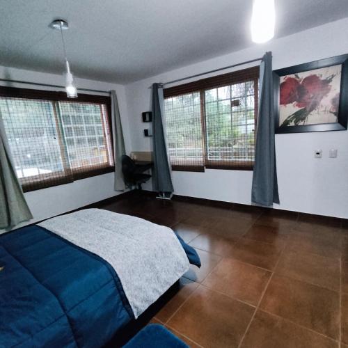 a bedroom with a blue bed and two windows at Finca el Nogal - Casa Entera Familiar Moderna con Amplio Jardín Atlixco puebla in Atlixco