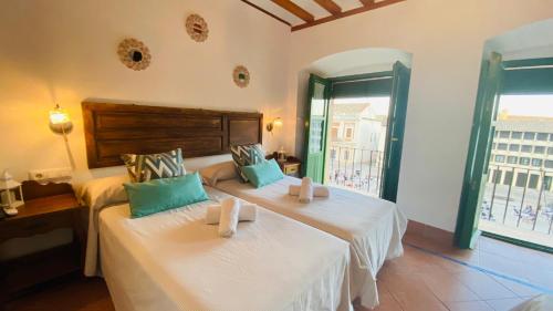 a bedroom with two beds with white sheets and green pillows at Hostel Plaza Mayor Corredera in Córdoba