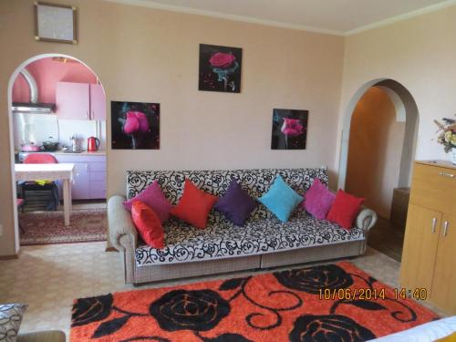 sala de estar con sofá y almohadas coloridas en Paradise Apartment, en Bishkek