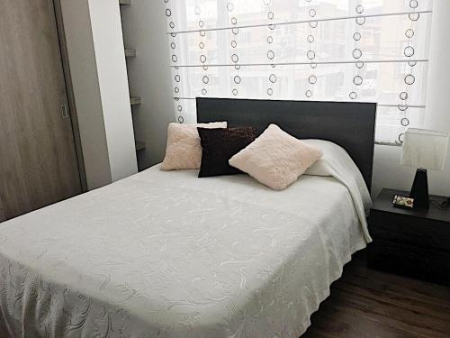 una camera da letto con un letto bianco e cuscini sopra di Espectacular apartamento con estacionamiento gratuito Chía N 2 a Chía