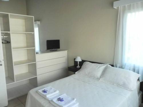 een slaapkamer met een wit bed en een televisie bij Alugar in Valeria del Mar