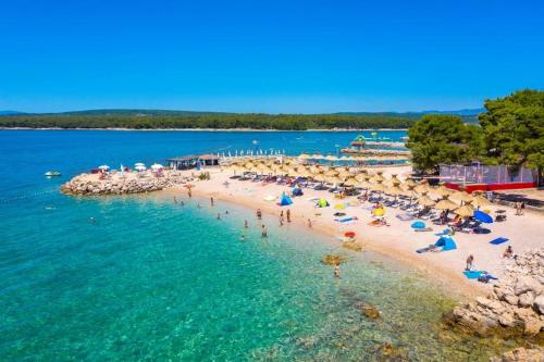 una spiaggia con ombrelloni e persone in acqua di Apartments Biserka a Punat
