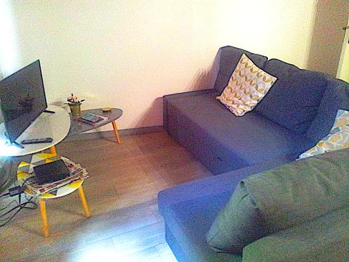 ein Wohnzimmer mit einem Sofa und einem Tisch mit einem Laptop in der Unterkunft Appartement en duplex - tout confort plein-centre in Lavaur