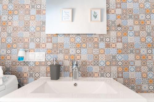 a bathroom with a sink and a tiled wall at BlueSky Ultra-Central Premium Apartment in Oradea