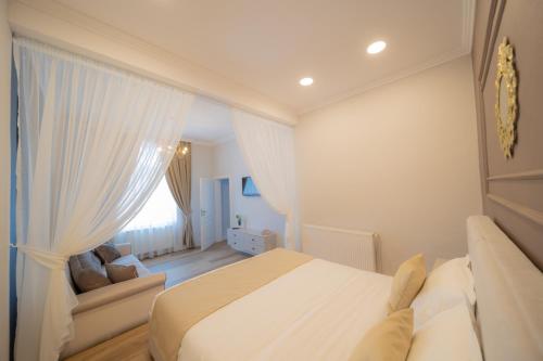 a white bedroom with a bed and a couch at BlueSky Ultra-Central Premium Apartment in Oradea