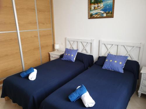 two beds in a room with blue sheets and blue pillows at Cozy apartment near the ocean in Corralejo