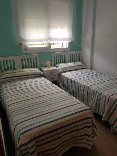 2 camas en una habitación con paredes verdes en Apartamento Blau Mar en Piles