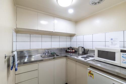 a white kitchen with a sink and a microwave at Admirals Motor Inn in Nelson