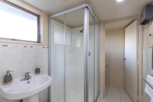 a bathroom with a glass shower and a sink at Admirals Motor Inn in Nelson