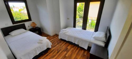 a bedroom with two beds and two windows at The Wind Sycamore Holiday Villas in Belek in Belek