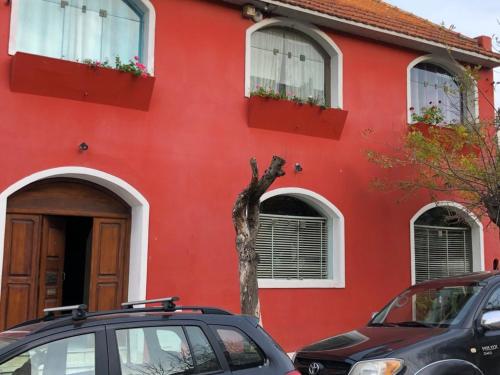 una casa roja con un coche aparcado delante de ella en varesse house en Mar del Plata
