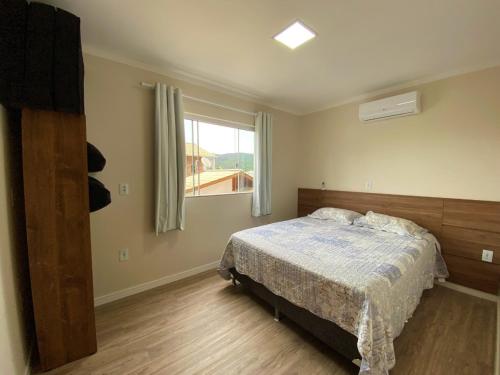 a bedroom with a bed and a window at Residencial Miguel in Bombinhas