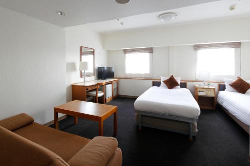 a hotel room with a bed and a couch at Hotel Resol Sasebo in Sasebo