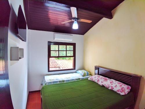 a bedroom with a green bed and a window at Casa do Loriba com Piscina - 700 metros da praia in São Sebastião