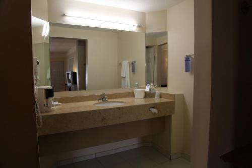 baño con lavabo y espejo grande en American Inn Hotel & Suites Parral, en Hidalgo del Parral