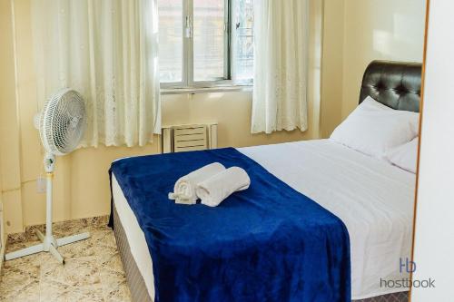 a bedroom with a bed with towels and a fan at Apto a 400 m da praia do Centro - WIFI 200MB - TV Smart - Cozinha equipada - Garagem - Ar condicionado in Rio das Ostras