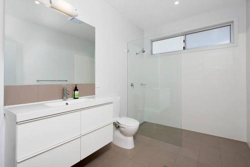 a white bathroom with a toilet and a sink at Ocean Views 41 in Anna Bay