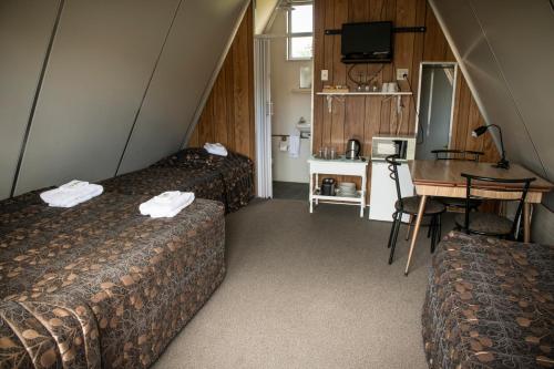 a room with two beds and a table and a desk at Rangiora Eco Holiday Park in Fernside