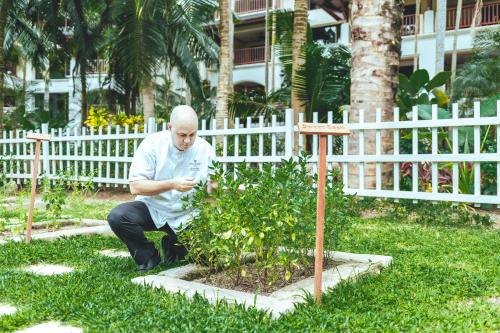a man sitting in the grass looking at his cell phone at JW Marriott Phuket Resort and Spa in Mai Khao Beach