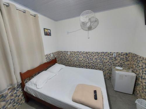 a small bedroom with a bed and a fan at Pousada do Leô in Mangaratiba