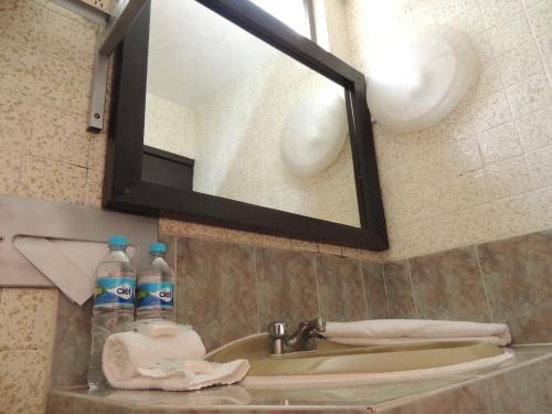 a bathroom sink with a mirror and two bottles of water at Hotel Lizbeth in Tula de Allende