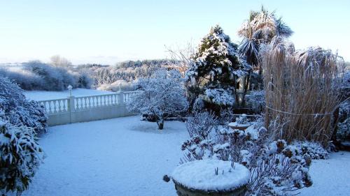 a garden covered in snow with a fence at Beautiful apartment with private pool near Tenby in Kilgetty