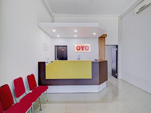 a waiting room with red chairs and a yellow counter at OYO Life 90570 Heboh Guest House Syariah in Ciwalengka