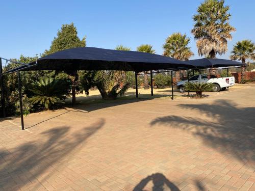 two black umbrellas in a parking lot with a truck at Tamarisk Guest Lodge in Benoni