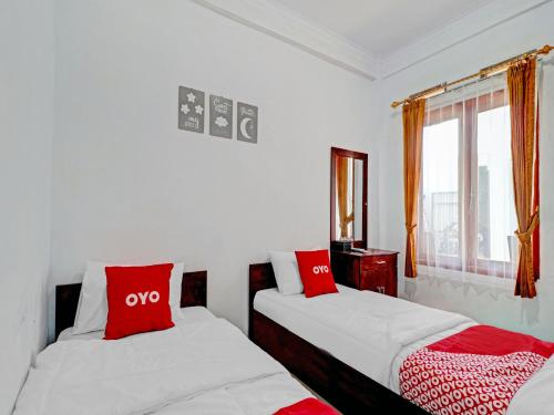 two beds in a room with red and white pillows at OYO Life 90570 Heboh Guest House Syariah in Ciwalengka
