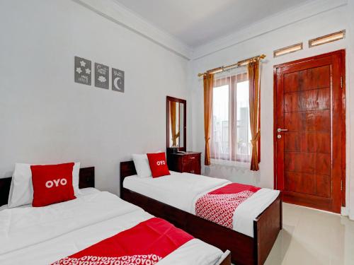 a bedroom with two beds and a window at OYO Life 90570 Heboh Guest House Syariah in Ciwalengka