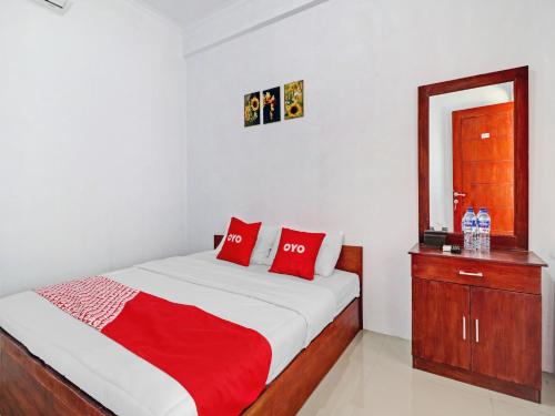 um quarto com uma cama com almofadas vermelhas e uma cómoda em OYO Life 90570 Heboh Guest House Syariah em Ciwalengka