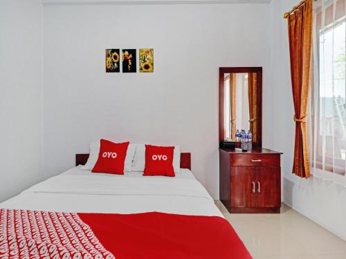 a bedroom with a bed with red pillows and a window at OYO Life 90570 Heboh Guest House Syariah in Ciwalengka