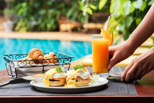 a table with a plate of food and a glass of orange juice at Palace Gate Hotel & Resort By EHM in Phnom Penh