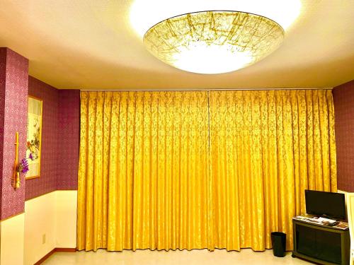 a room with a yellow curtain and a chandelier at 犬山モダンルーム in Inuyama